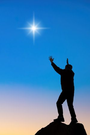 Man praying and worshiping with both hands raised towards the first star, backgrounds for Christmas vertical imageの写真素材