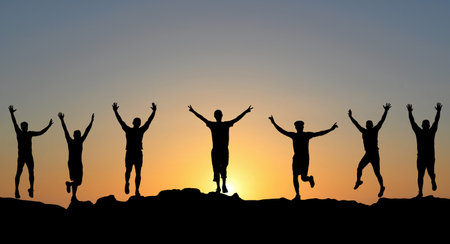 Silhouette of happy men with arms raised up against beautiful sky at sunsetの写真素材