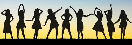 Silhouettes of girls playfully interact against the backdrop of a stunning sunsetの写真素材