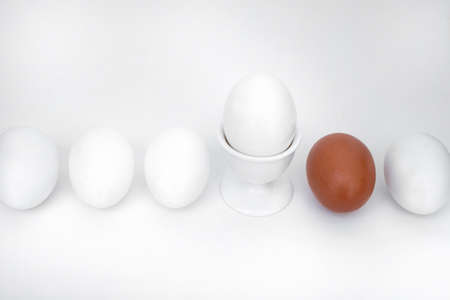 White eggs, a cup, and a brown egg for contrast and accent in the compositionの写真素材