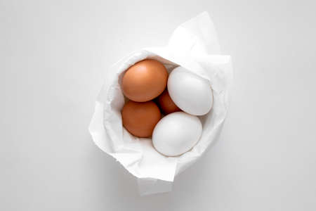 White and brown eggs in a basket on a white backgroundの写真素材