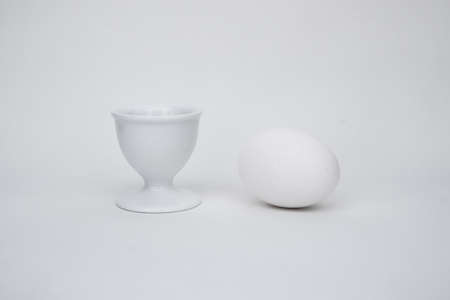 White egg on a white background, with a cupの写真素材
