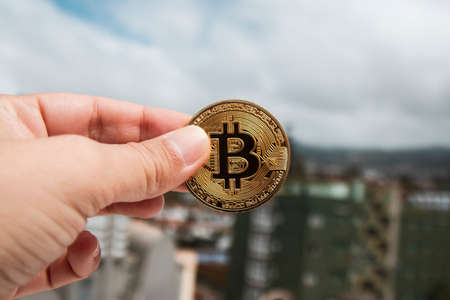 A hand holds a bit coin against the skyの写真素材