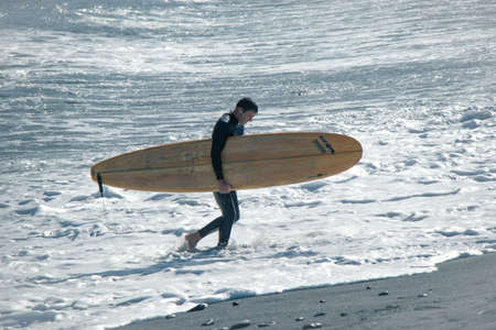 Picture of a man with a surfboard on the beach.