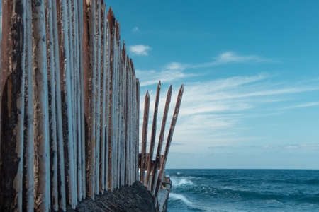 A wooden fence by the sea and the waves hit the rock and the fenceの写真素材