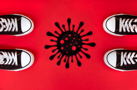 Social distance, Legs of people distant, sneakers on a red background, separated by a virus,...