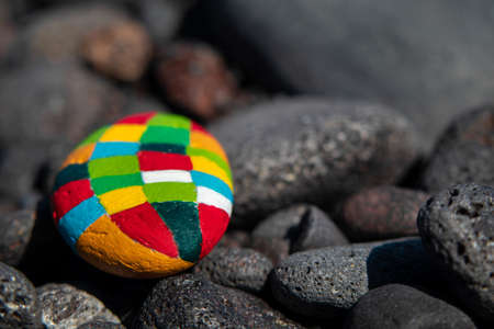 Dark stones with an emphasis on a small hand-painted stone with many colorsの写真素材