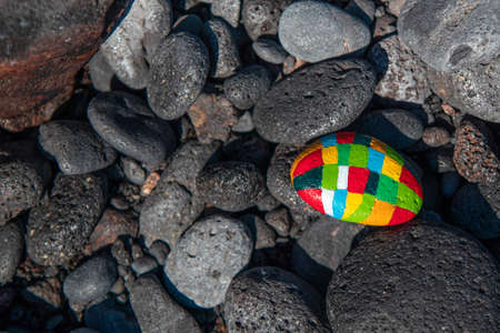 Dark stones with an emphasis on a small hand-painted stone with many colors