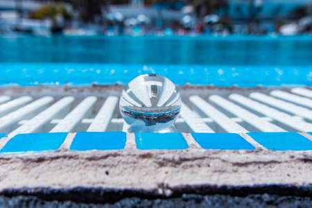 Crystal ball reflecting geometric white lines of the pool, abstract composition in white and blue in summerの写真素材