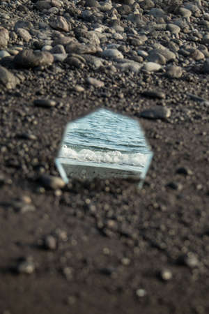 A mirror in the sand reflecting the ocean and the waves