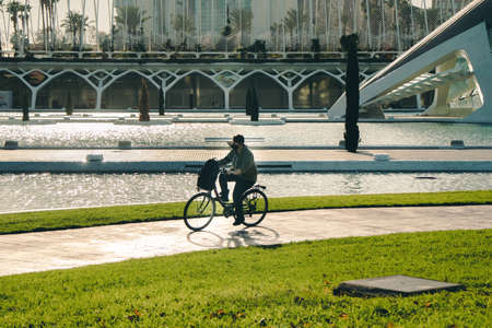 A man rides a bicycle in the Queen Sofia Palace of Arts Park, futuristic architectureのeditorial素材