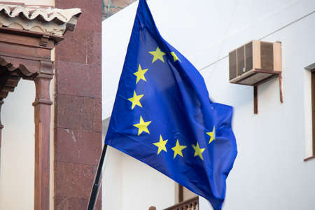 European Union flag blowing in the wind on the street in front of a buildingの写真素材