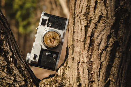 Old camera with bitkane on the lens in the wooden park