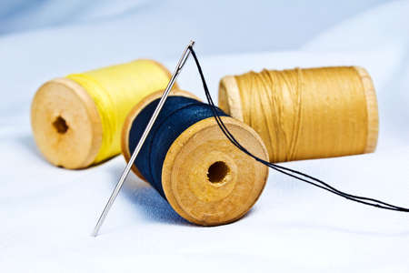 Spool of thread and needle on fabric.の写真素材