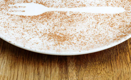 White plate with cacao powder on a wooden surface