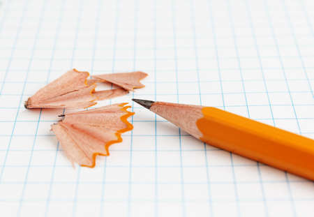 Yellow pencil with shavings on a paper sheet