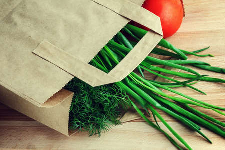 Paper bag with vegetables on woodの写真素材