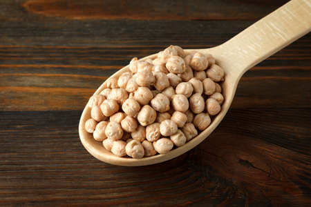 Chickpeas in a wooden spoon on woodの写真素材