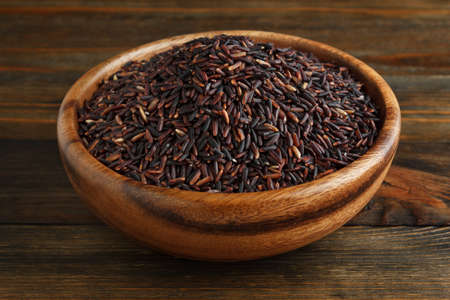 Black rice in a wooden bowl on wood closeupの写真素材