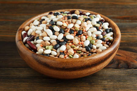 Mix of beans in a wooden bowl on wood closeupの写真素材