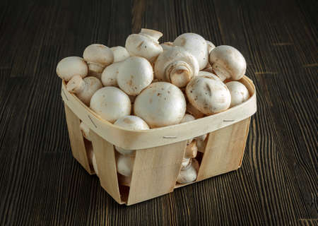 Small basket with  mushrooms on wood close-upの写真素材