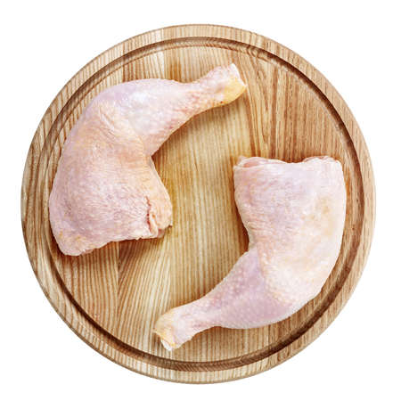 Chicken legs on a round cutting board isolated on whiteの写真素材