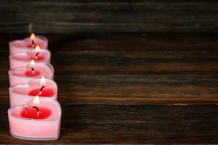 Burning candles in the shape of a heart on wood close-upの写真素材