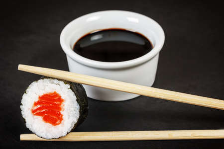 Sushi roll with chopsticks and soy sauce over black background close-upの写真素材