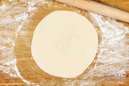 Wooden board with flour, dough and rolling pin close-upの写真素材