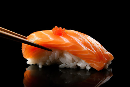 Salmon sushi with chopsticks isolated on black background. Japanese foodの素材