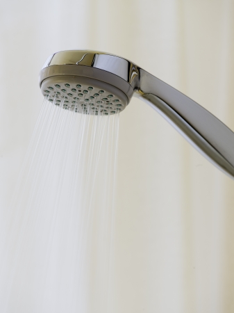Showerhead with spraying water on backgroundの写真素材