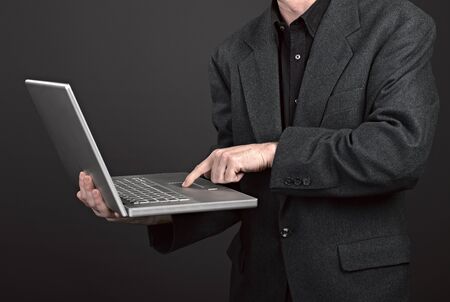 Businessman holding his laptop on blackの写真素材