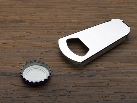 close up of bottle opener and cap on wooden backgroundの写真素材
