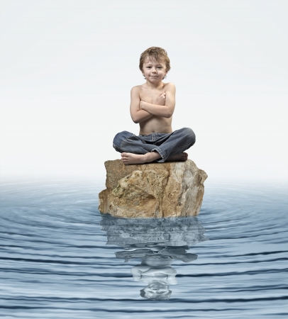 Zen Kid on rock in waterの写真素材
