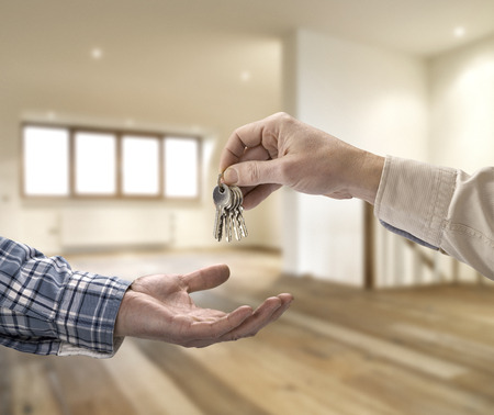 Realtor giving house key to buyer in empty roomの写真素材