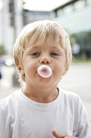 Child blowing a bubble gum on a blurred backgroundの写真素材