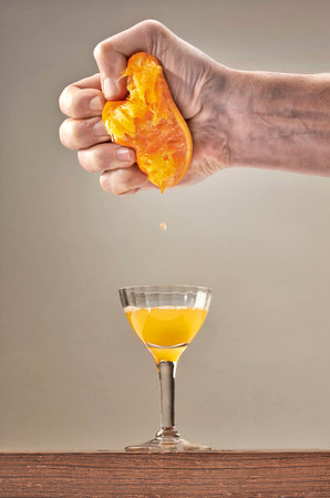 Fresh Squeezed Orange Juice by male hand and falling in juice HAS elegant glassの写真素材