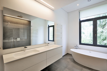 Bathtub in corian, Faucet and shower in tiled bathroom with windows towards gardenの写真素材