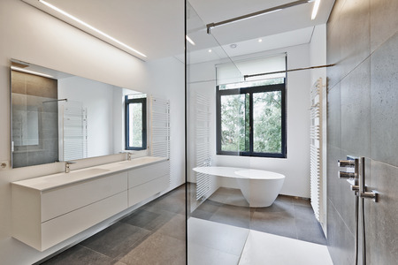 Bathtub in corian, Faucet and shower in tiled bathroom with windows towards gardenの写真素材