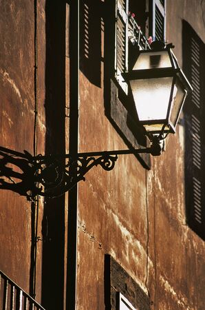 Brown Roman wall with street lamp and windows at golden hour.の写真素材