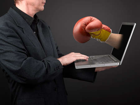Man in black shirt and suit holding a laptop and win Boxing glove punchの写真素材