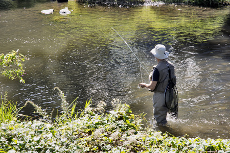 HAN-SUR-LESSE, BELGIUM - SEPTEMBER 10, 2016: Fisherman fishing on the Lesse river with forest in the backgroundのeditorial素材