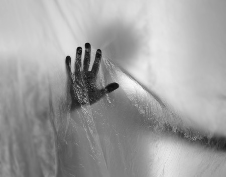 Silhouette of a ghost hand behind transparent plasticの写真素材