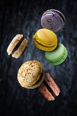 Assorted multi flavoured macaroons floating against dark backgroundの写真素材