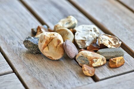 Lot of little rocks on wooden table at sunsetの写真素材