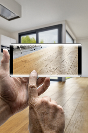 Two hands holding a mobile Smartphone and take a picture in a Modern luxury living room with wooden floorの写真素材