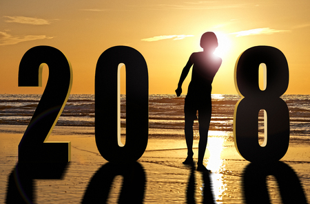 Beautiful sunset on ocean in summer time with 2018 numbers and silhouetteの写真素材