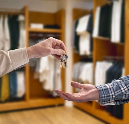 Man is handing a house key to a other man in modern dressing roomの写真素材