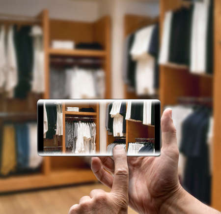 Two hands holding a mobile Smartphone and take a picture of a modern dressing roomの写真素材