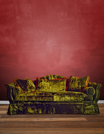 Luxurious green velvet sofa with textured red wallの写真素材